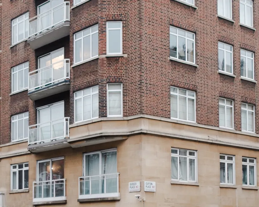 Corner of a red-brick apartment building in London with balconies and large windows
