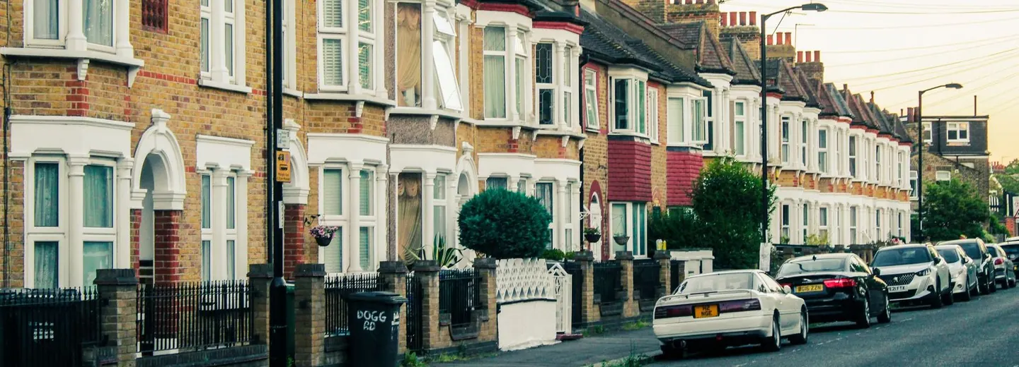Victorian terraced homes along a London street at dusk, with cars parked along the road