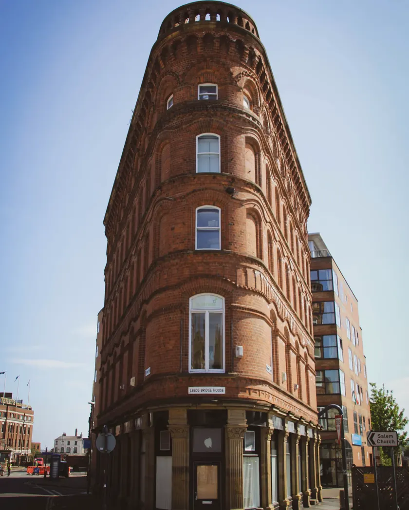 Curved red-brick Victorian commercial building on a street corner under a clear blue sky