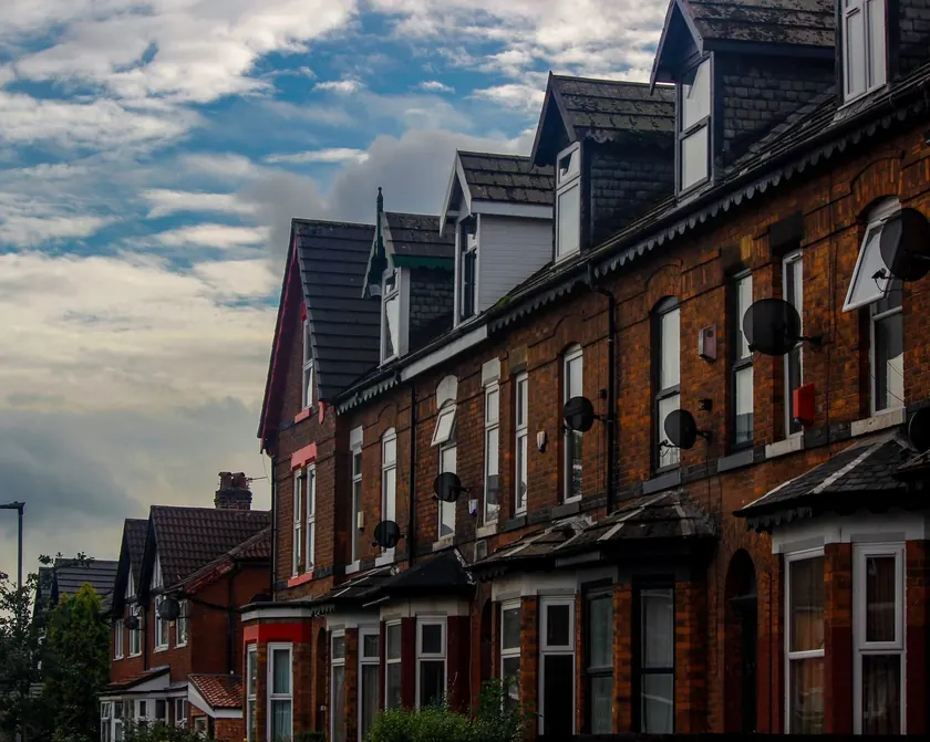 Red-brick Victorian terraced houses under a blue sky with clouds in Manchester